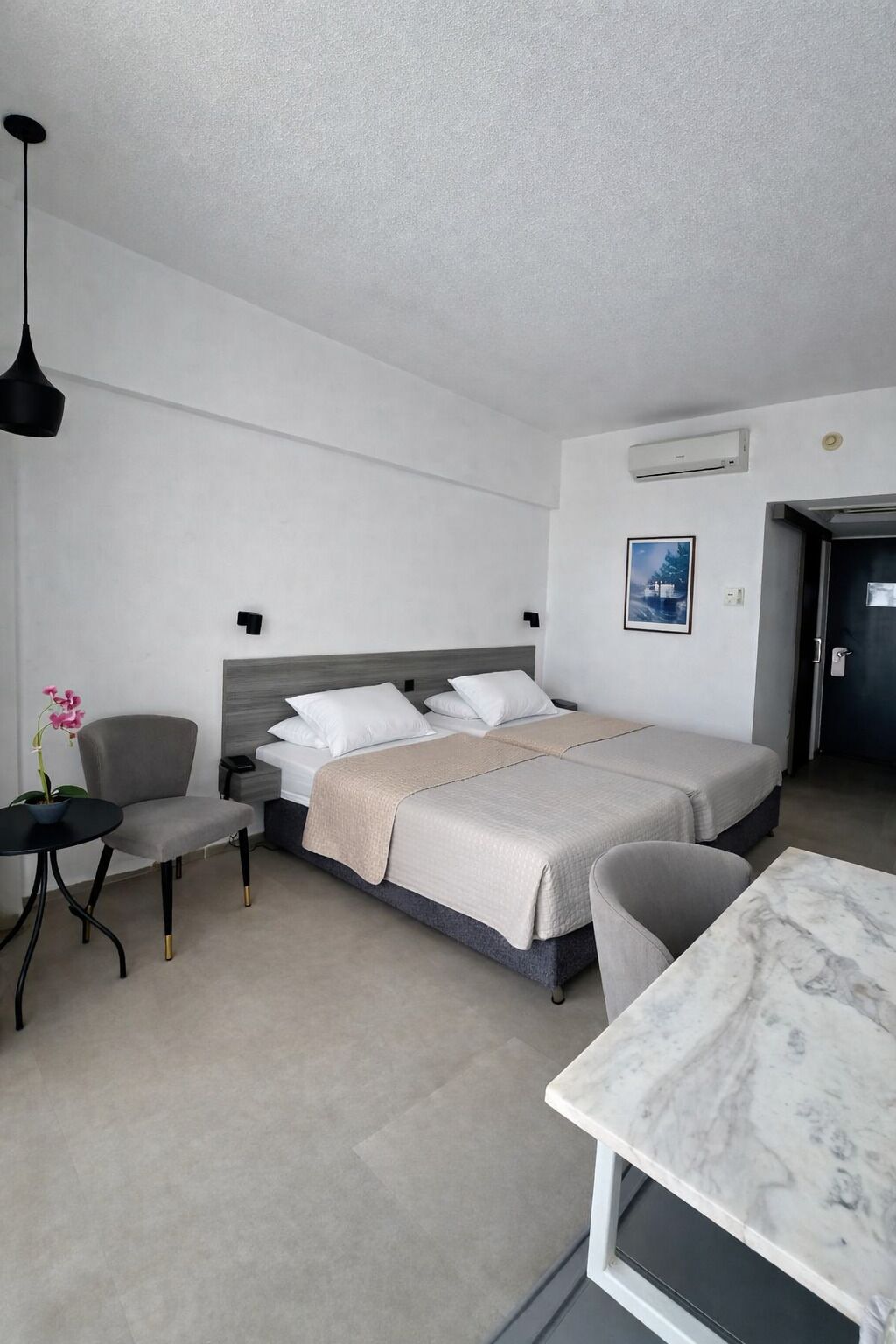 Una habitación de hotel moderna con una cama, un escritorio, una silla y una mesita.