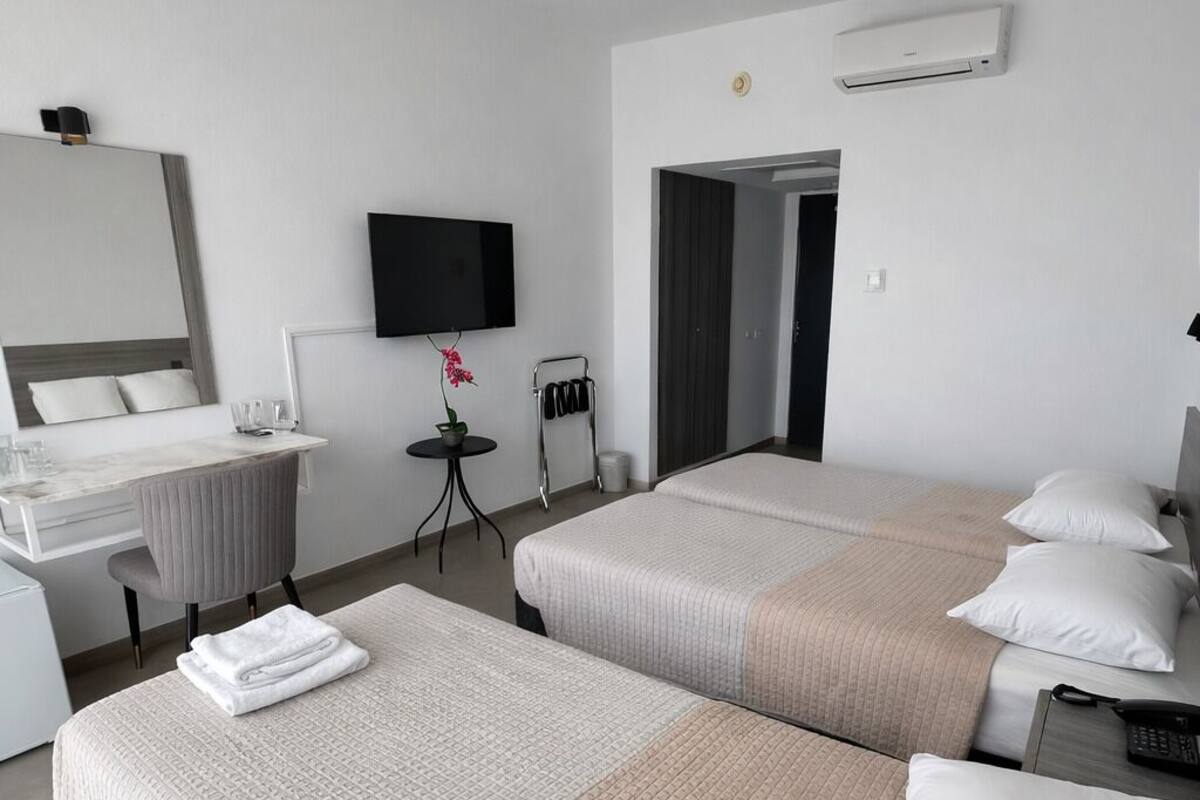 A hotel room with two beds, a TV, a desk, and a mirror.