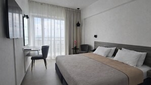 Une chambre d’hôtel moderne équipée d’un lit, d’un bureau, d’une chaise et d’un téléviseur.