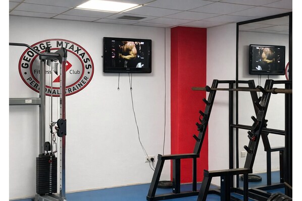 A gym with exercise equipment, a television, and a red wall.