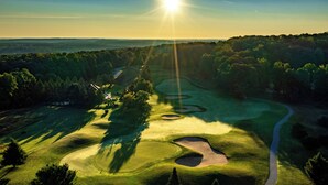 Een golfbaan met een kronkelend pad, zandbunkers en een heldere lucht.
