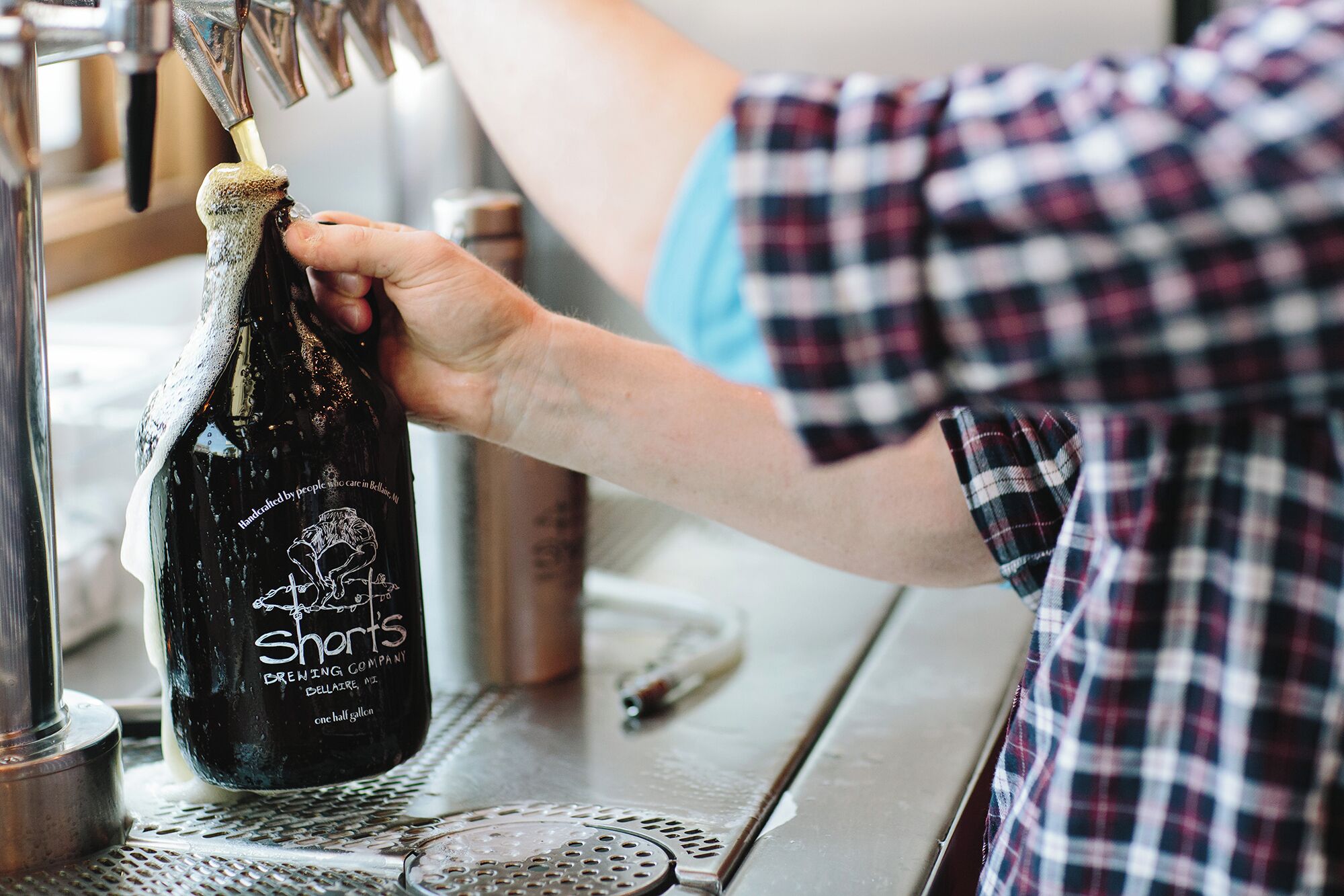 Una persona vertiendo cerveza de Shorts Brewing Company en un grifo.