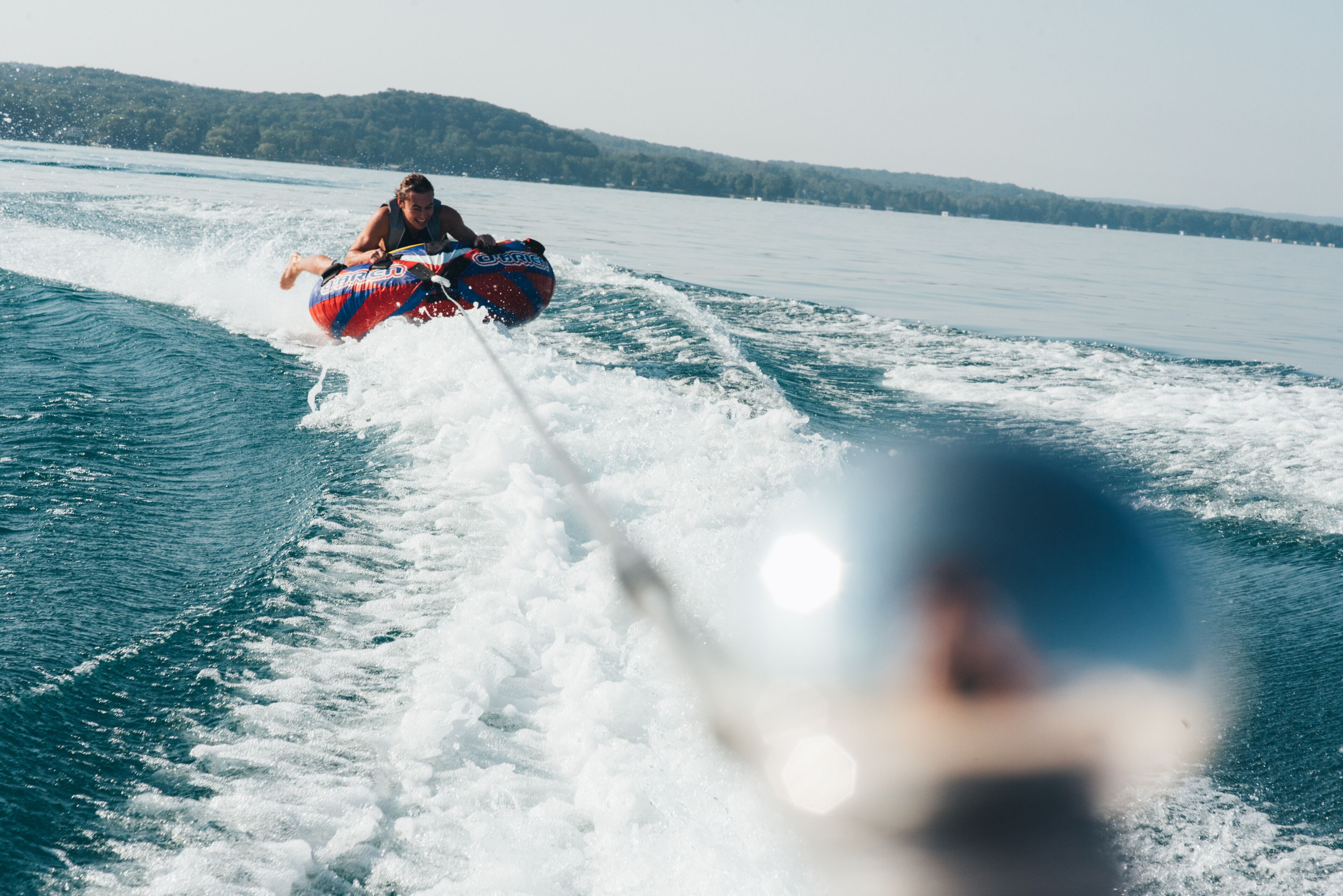 A person wakeboarding on a lake with a boat creating waves.