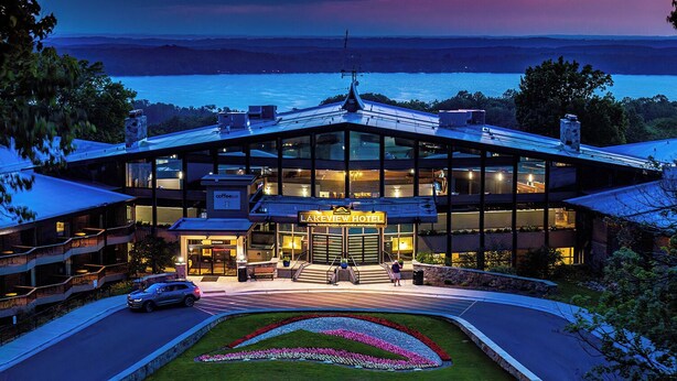Een modern hotel met een glazen gevel, een zichtbaar restaurant en een aangelegde entree.