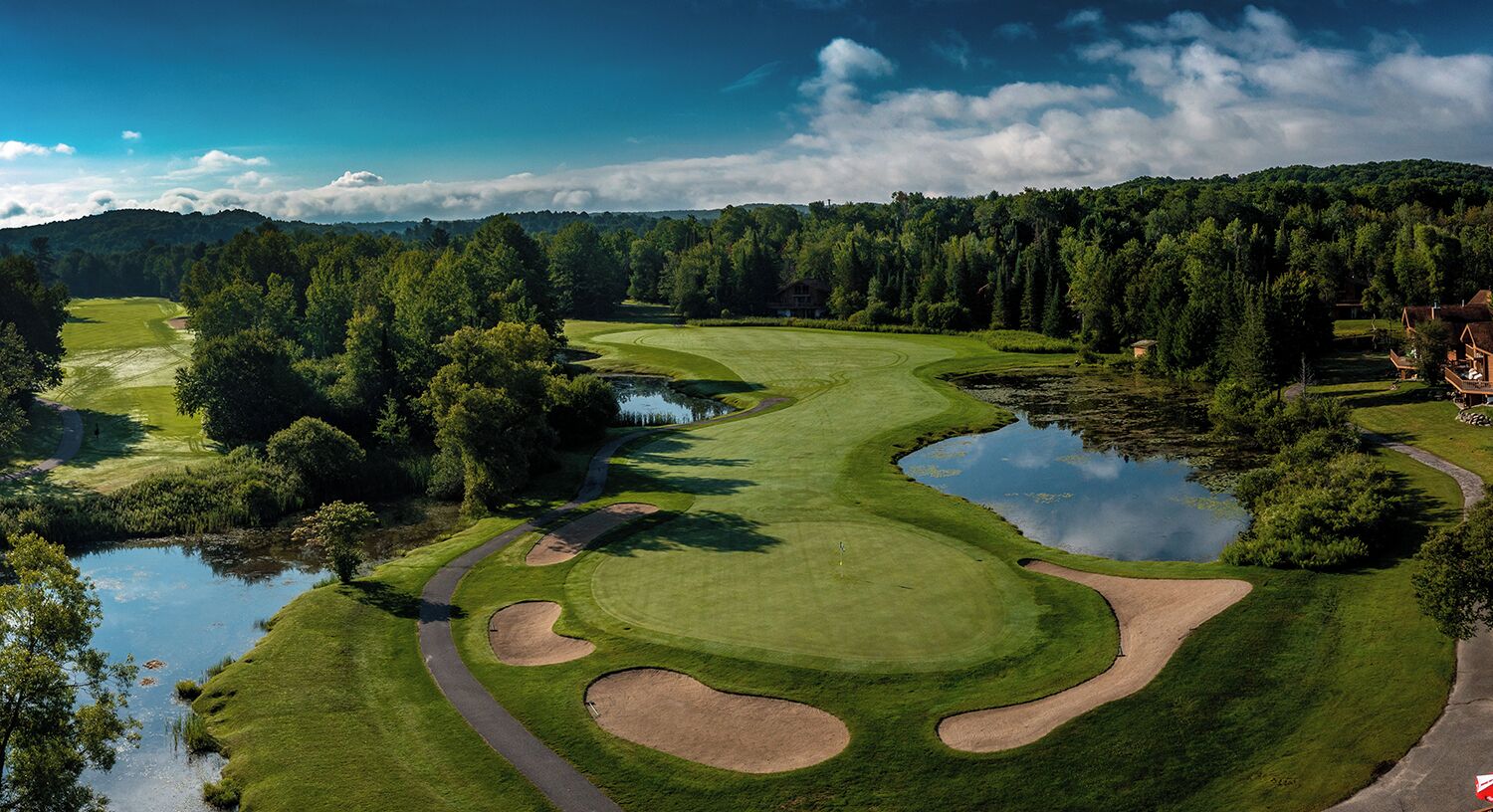 Un campo de golf con búnkeres, peligros de agua y un estanque.