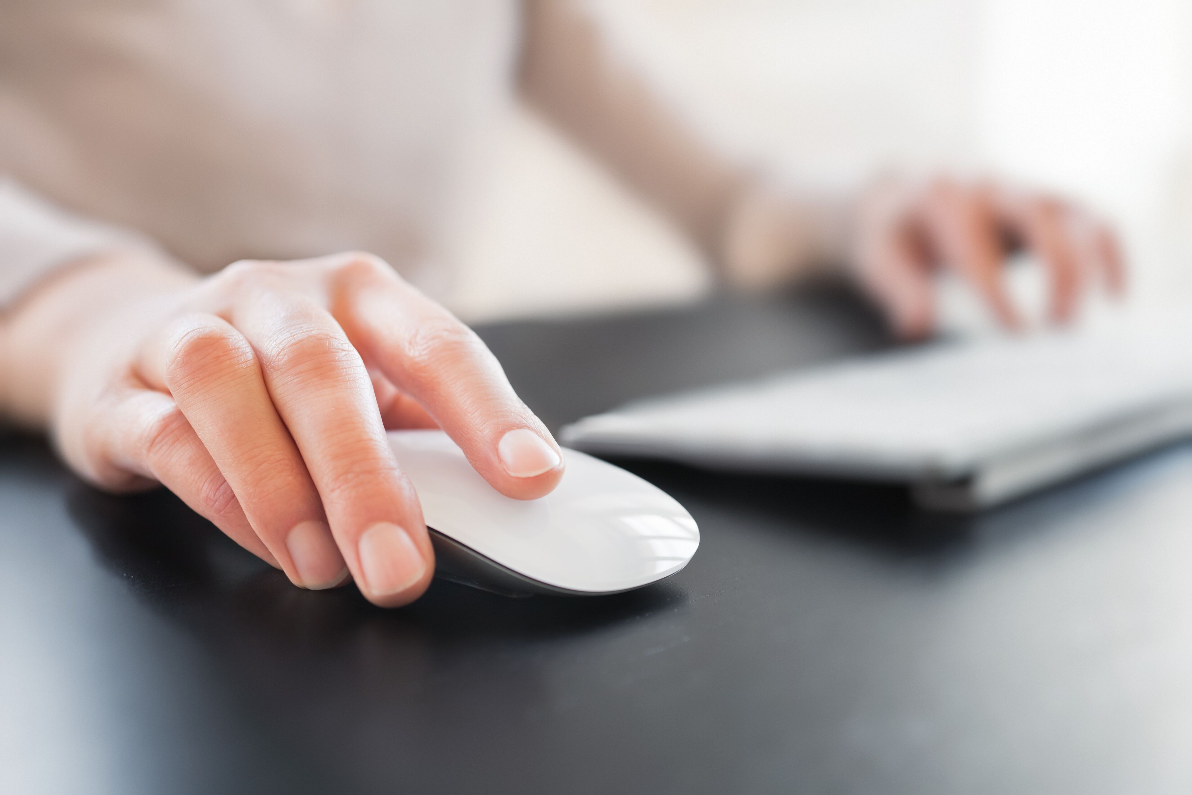 A close-up of a hand using a white touchpad on a black surface.