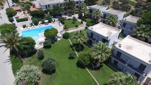Un barrio residencial con edificios modernos, una piscina y jardines bien cuidados.