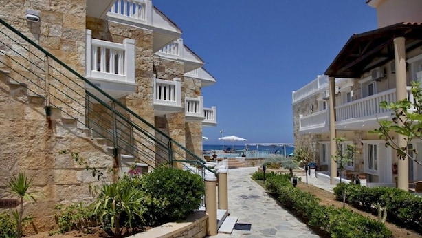A stone pathway leading to a beach with white balconies and a clear blue sky. - Jo-An Beach Hotel (Rethymno)