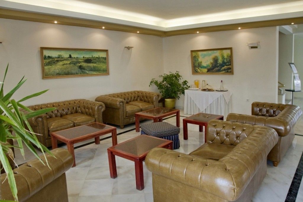 A spacious living room with leather sofas, wooden coffee tables, and two paintings on the walls.