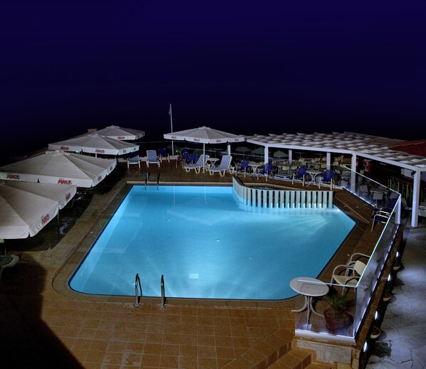 A nighttime swimming pool with lounge chairs and umbrellas. - Jo-An Beach Hotel (Rethymno)