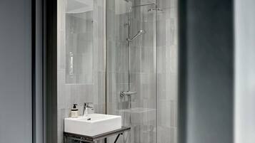 Une salle de bain moderne avec une douche à parois de verre, un lavabo blanc et une douchette à main.