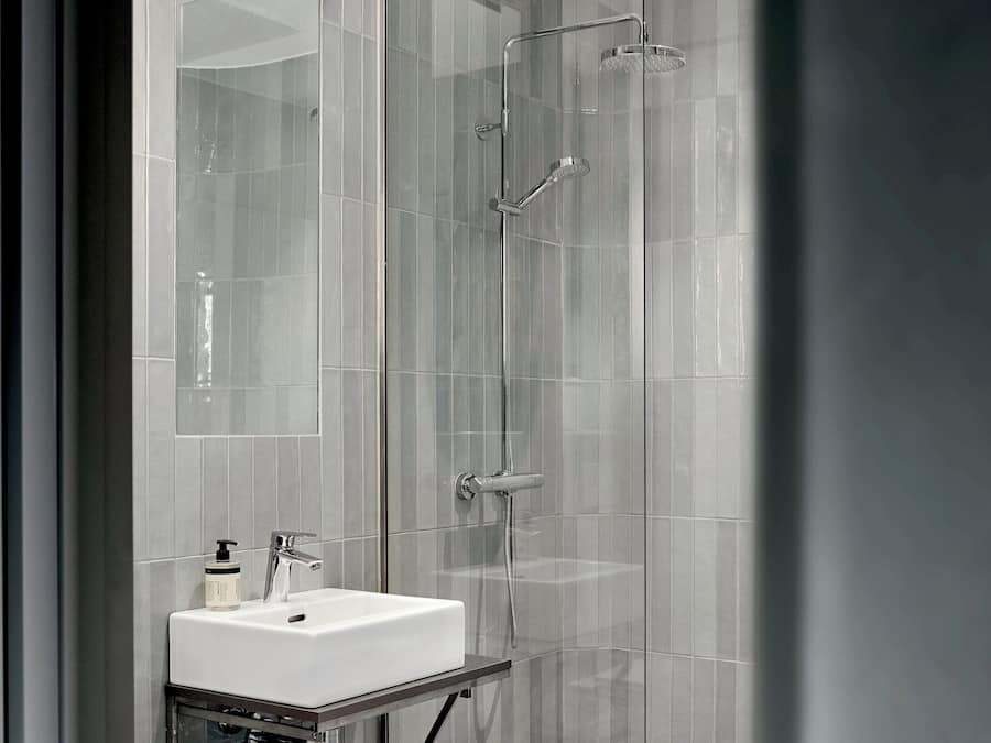 Une salle de bain moderne avec une douche à parois de verre, un lavabo blanc et une douchette à main.