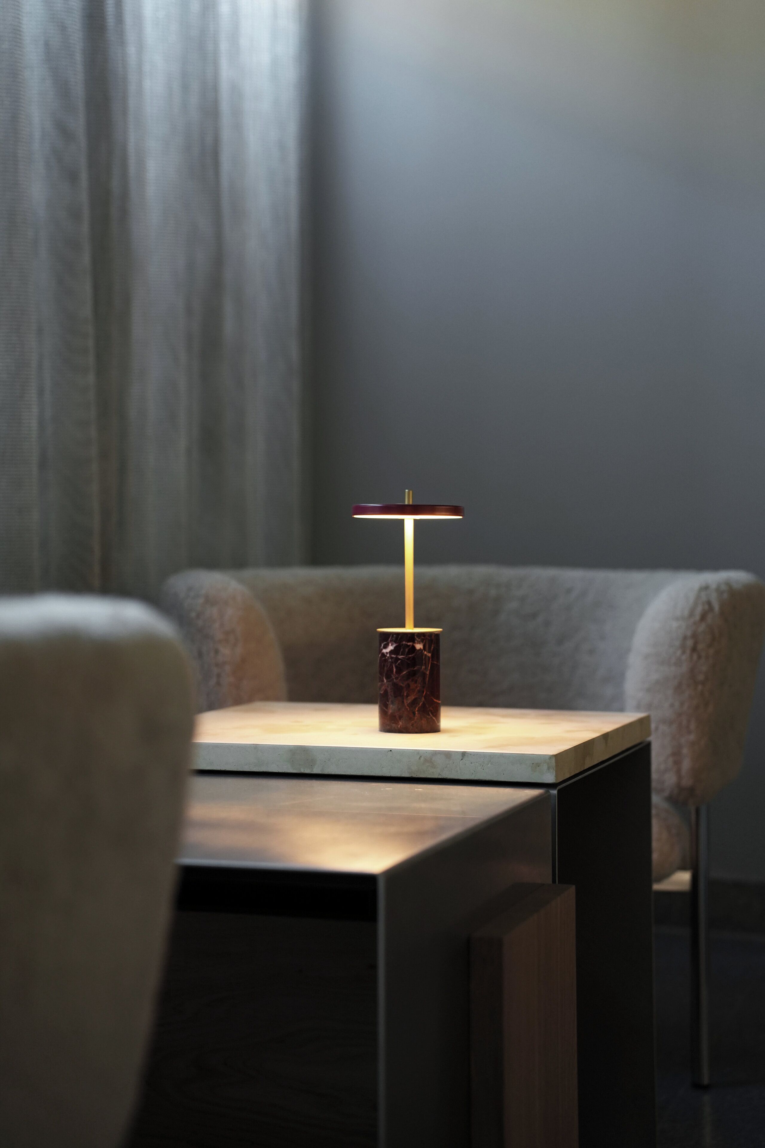 A modern table with a marble base and a minimalist lamp.