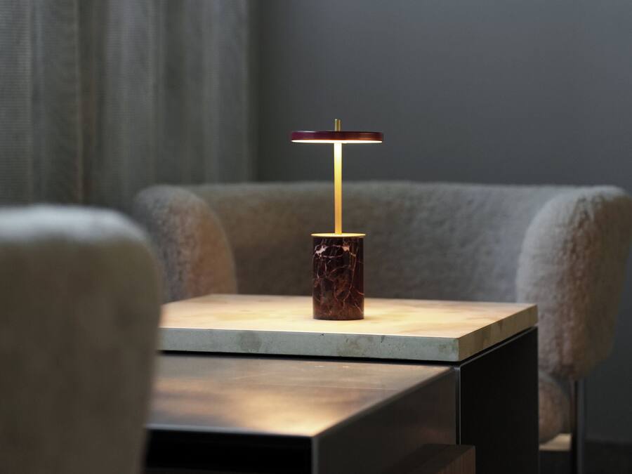 A modern table with a marble base and a minimalist lamp.