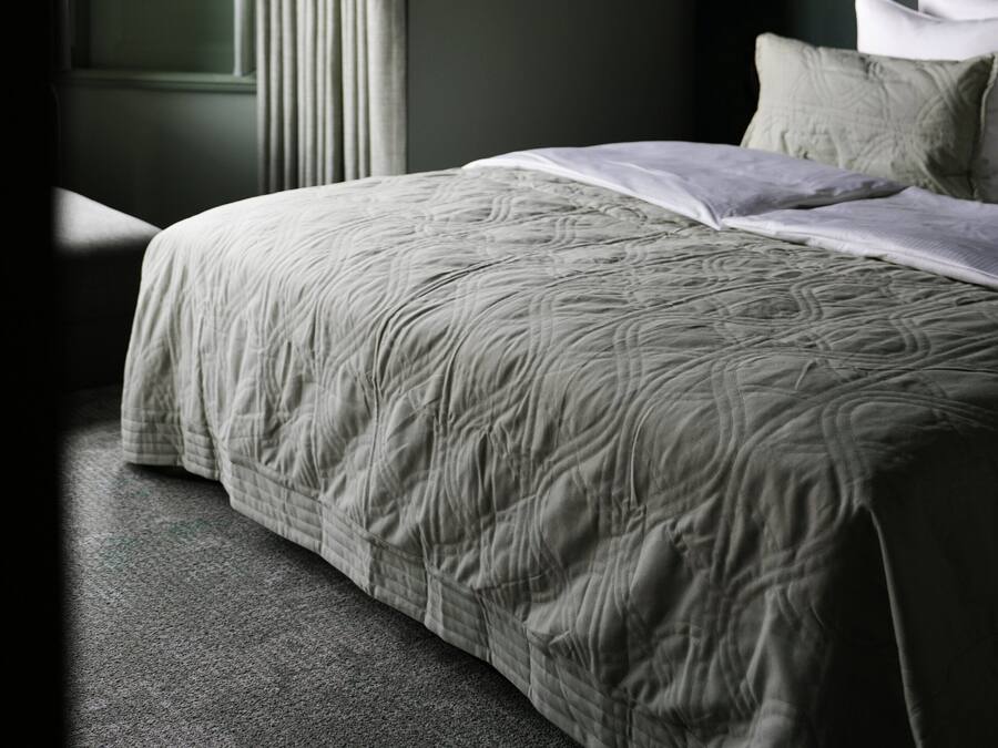 A bedroom with a large bed, a window with curtains, and a dark wall.