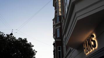 A hotel sign with the name 'HANS' illuminated against a clear sky.