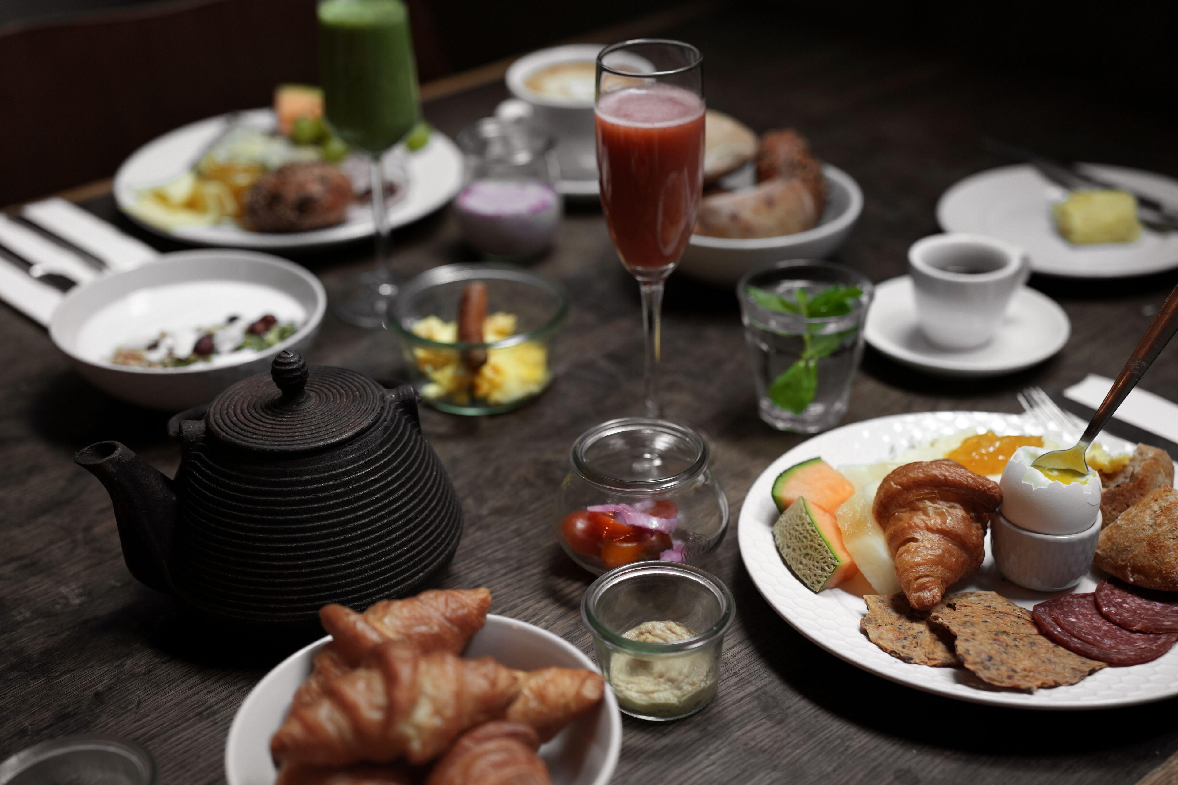 Un desayuno servido con platos de comida, una tetera y diferentes condimentos.