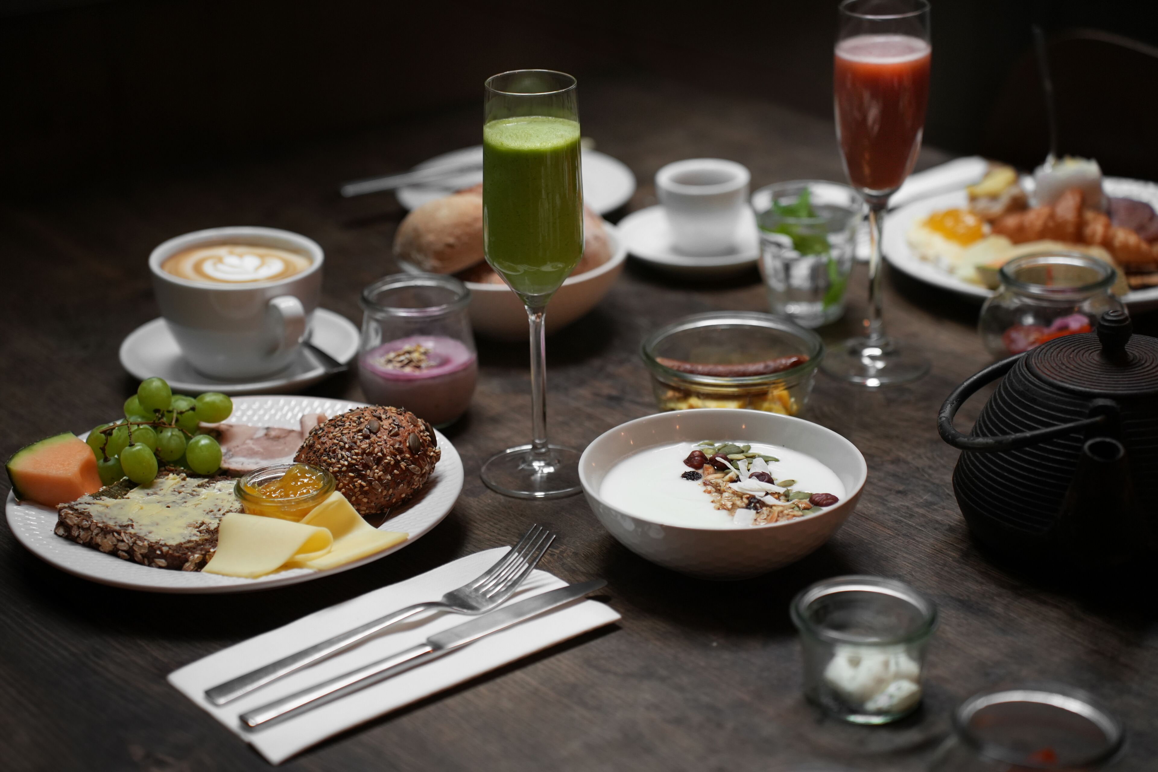 A table set with various breakfast items including toast, fruit, a green smoothie, and a cup of coffee.