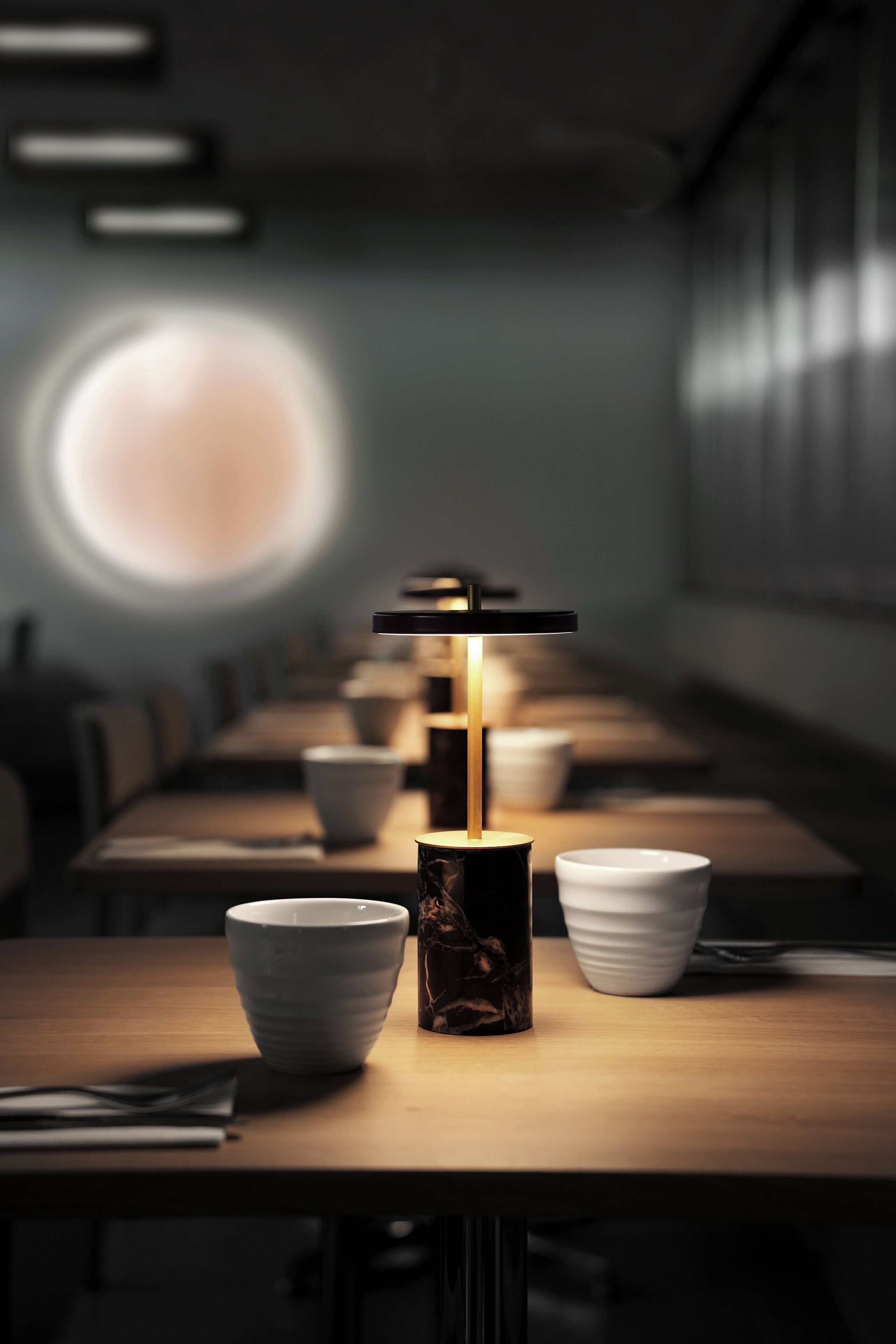 A long table with white bowls and a candle in the center.