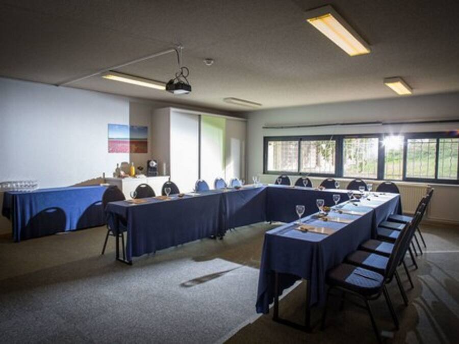 Un salón de conferencias con una mesa larga, sillas y un proyector.