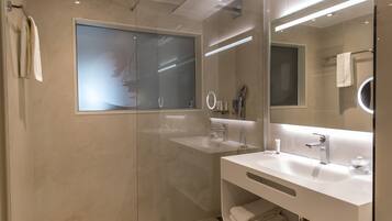 A modern bathroom with a glass shower enclosure, a white sink, and a large mirror.