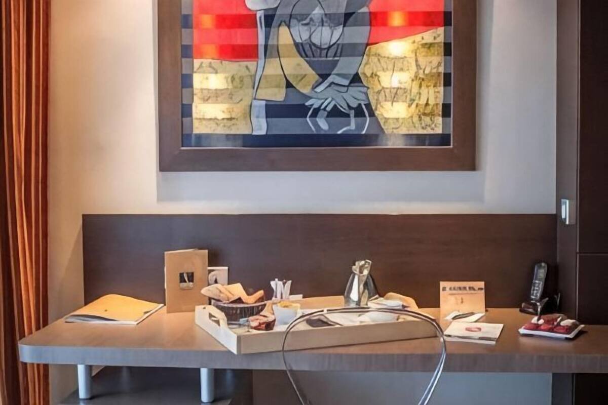 Una mesa de recepción con una obra enmarcada en la parte superior, un teléfono y una pequeña mesa con objetos.