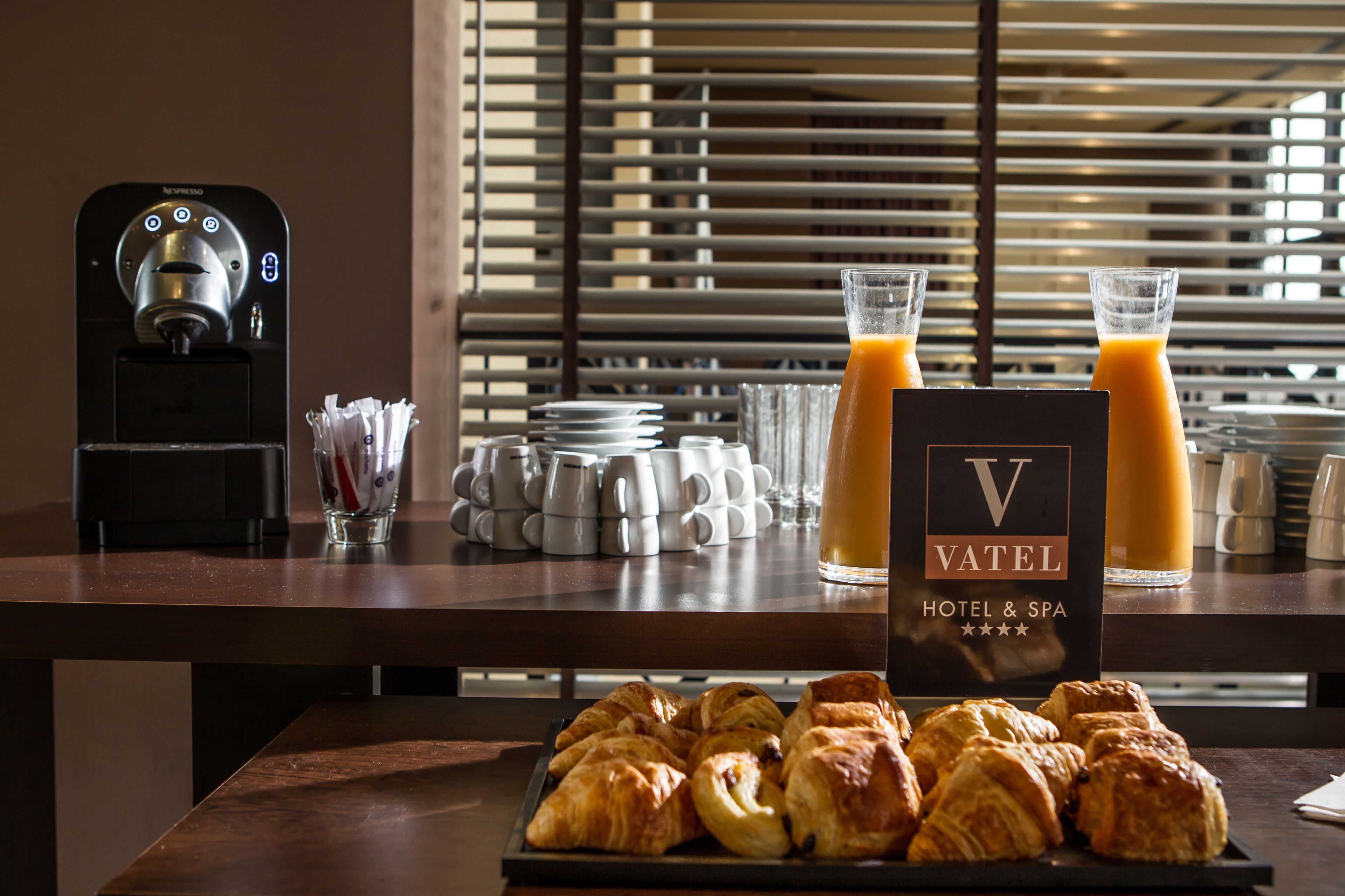 A breakfast setup with croissants, coffee mugs, and a juice dispenser.
