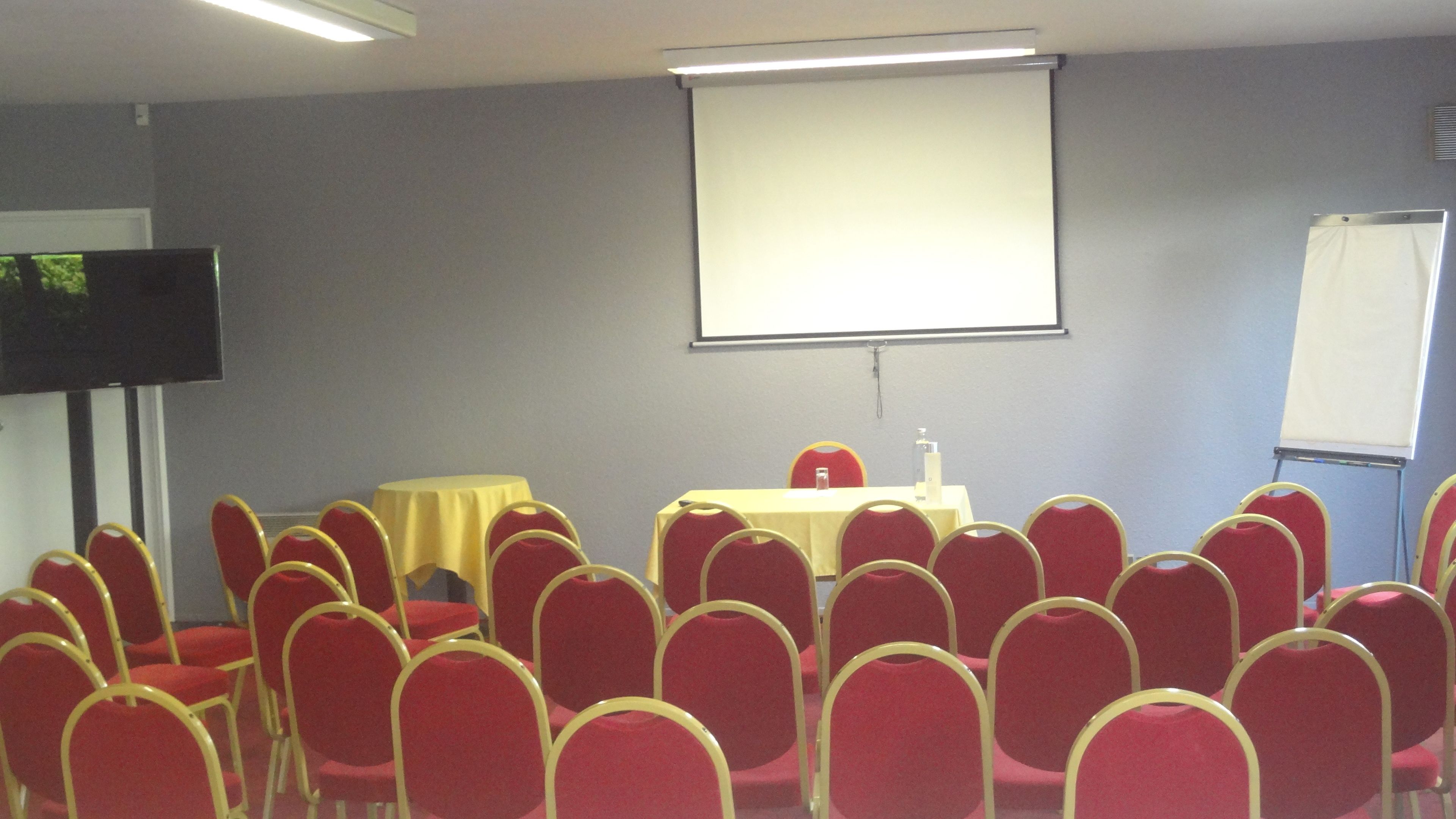A conference room with a table, chairs, a projector screen, and a whiteboard.