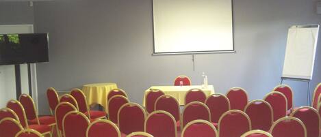A conference room with a table, chairs, a projector screen, and a whiteboard.