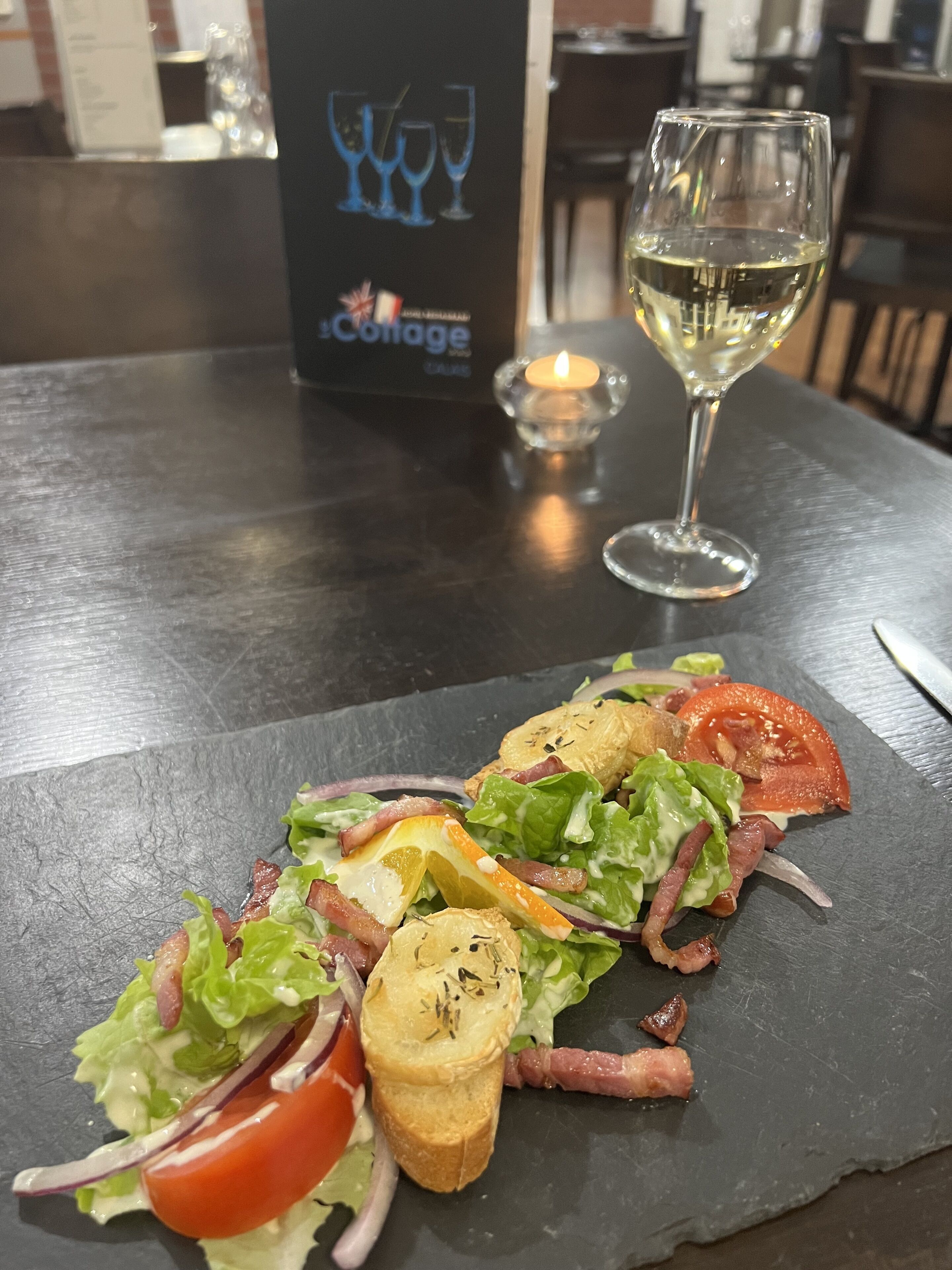A table with a black slate top, a glass of white wine, and a menu titled "The Cottage".