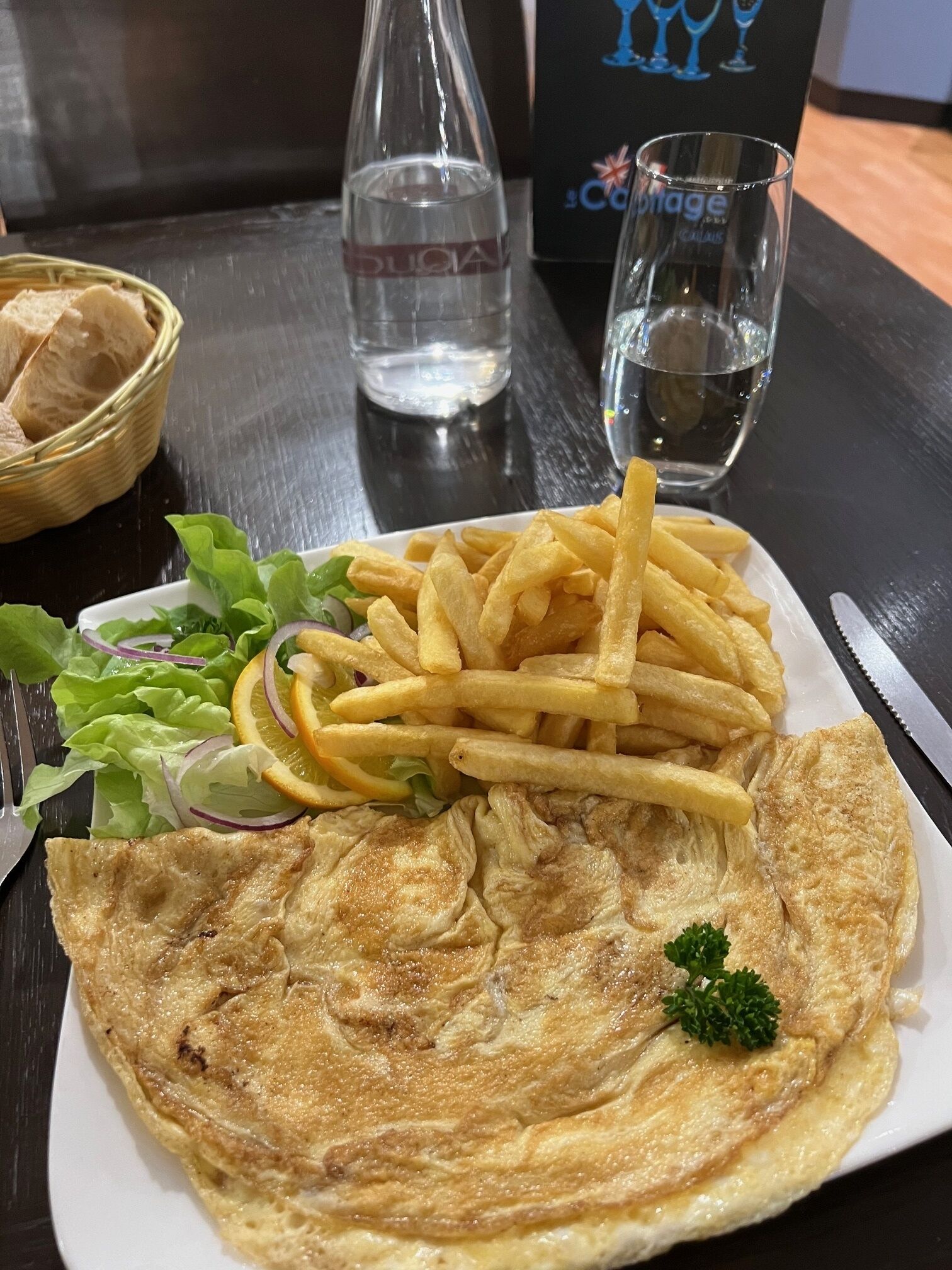 A plate of food with a fish pancake, fries, and a side salad.