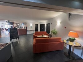 Un vestíbulo moderno con zona de estar, mostrador de recepción y planta en maceta.