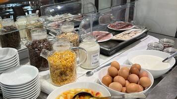 Un mostrador de buffet con diversos alimentos, incluyendo frutas, cereales y productos lácteos.