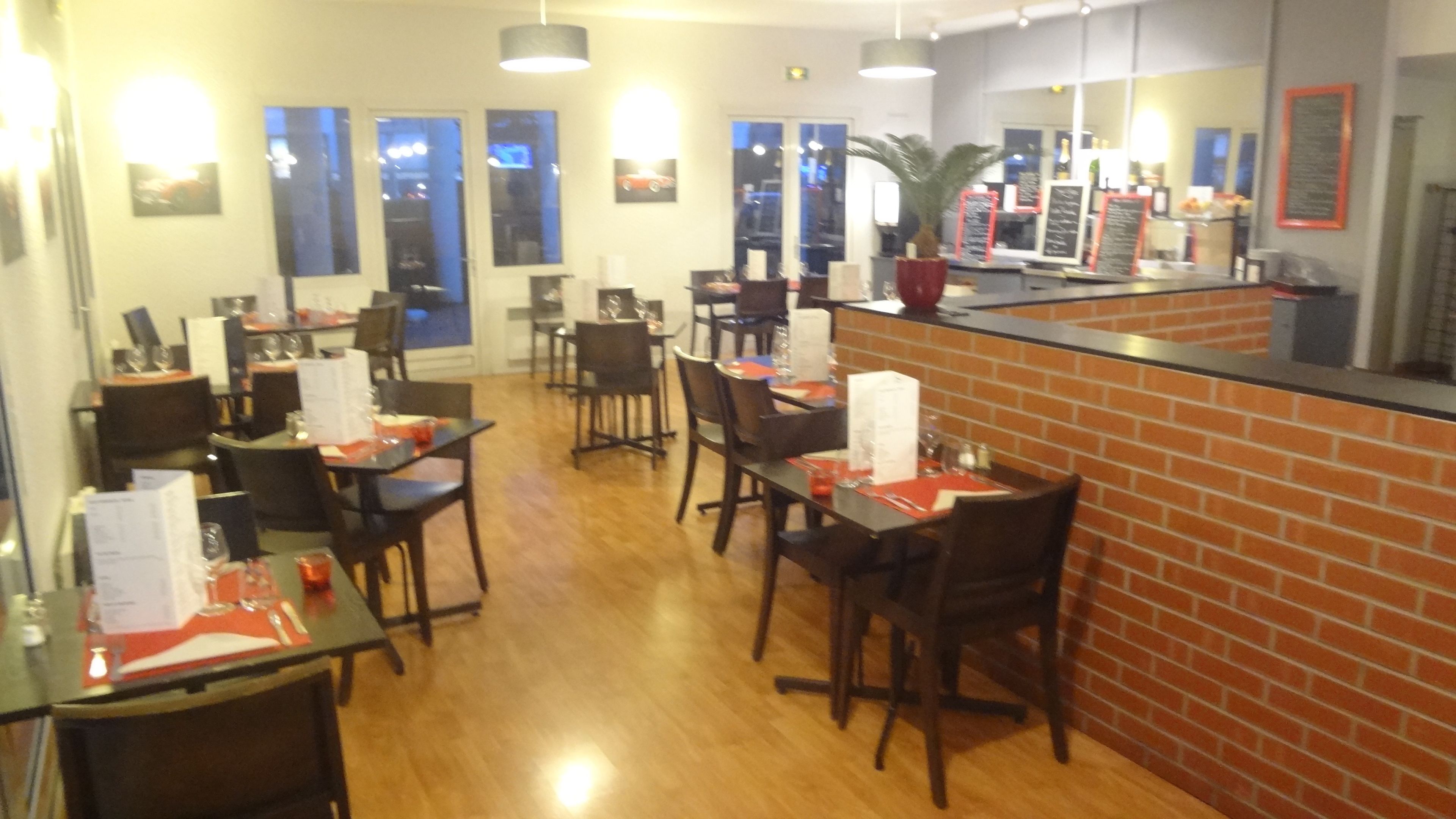 Een restaurant met houten tafels en stoelen, een accentmuur van baksteen, en een toonbank met menuborden.