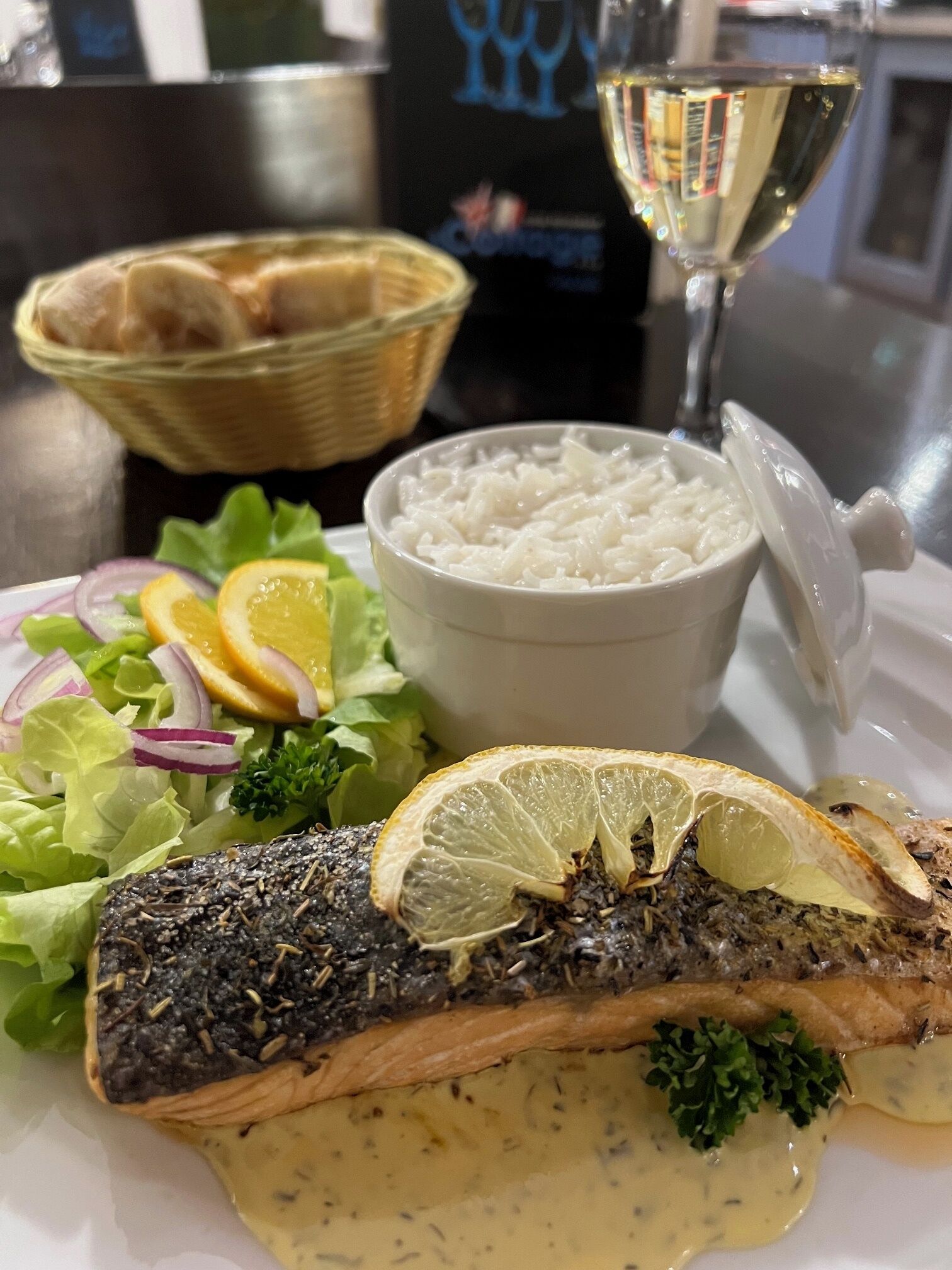 A plate with a fish fillet, lemon slices, and a side salad.
