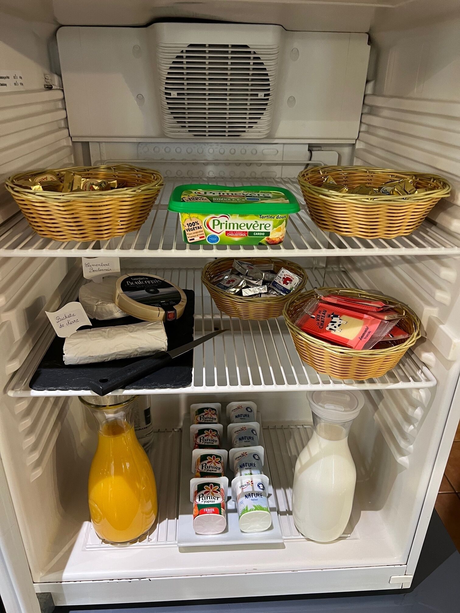 A refrigerator stocked with various food items including baskets, dairy products, and condiments.