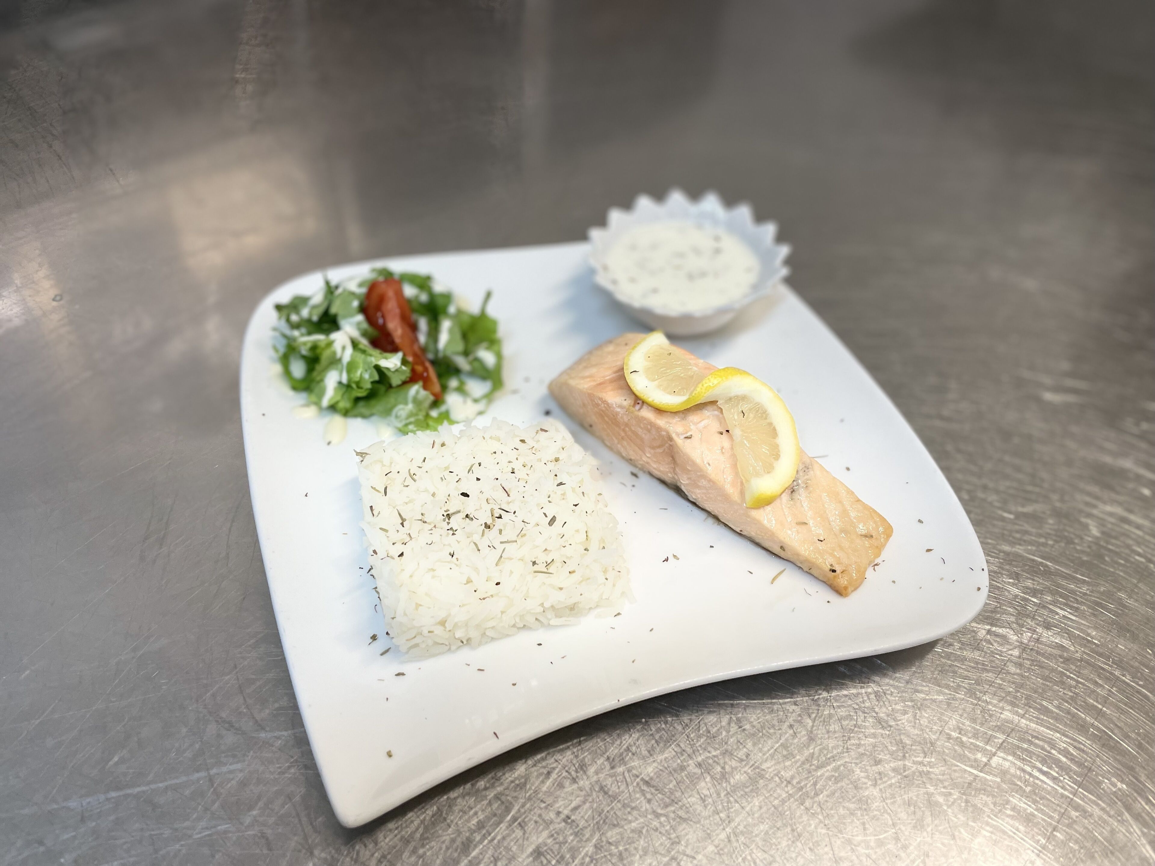 A plate with salmon, rice, and a salad.