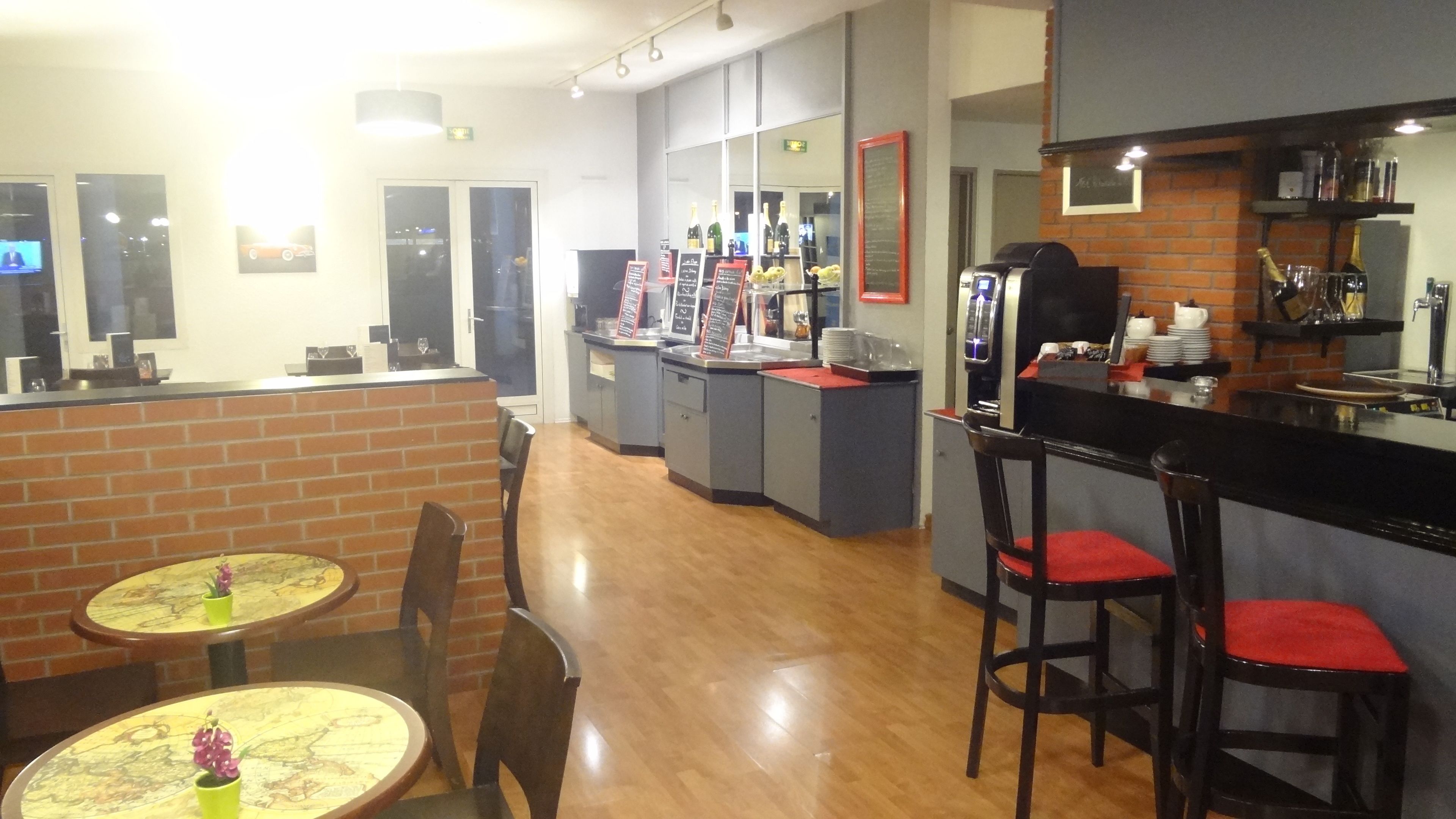 A restaurant with brick walls, wooden floors, and bar seating.