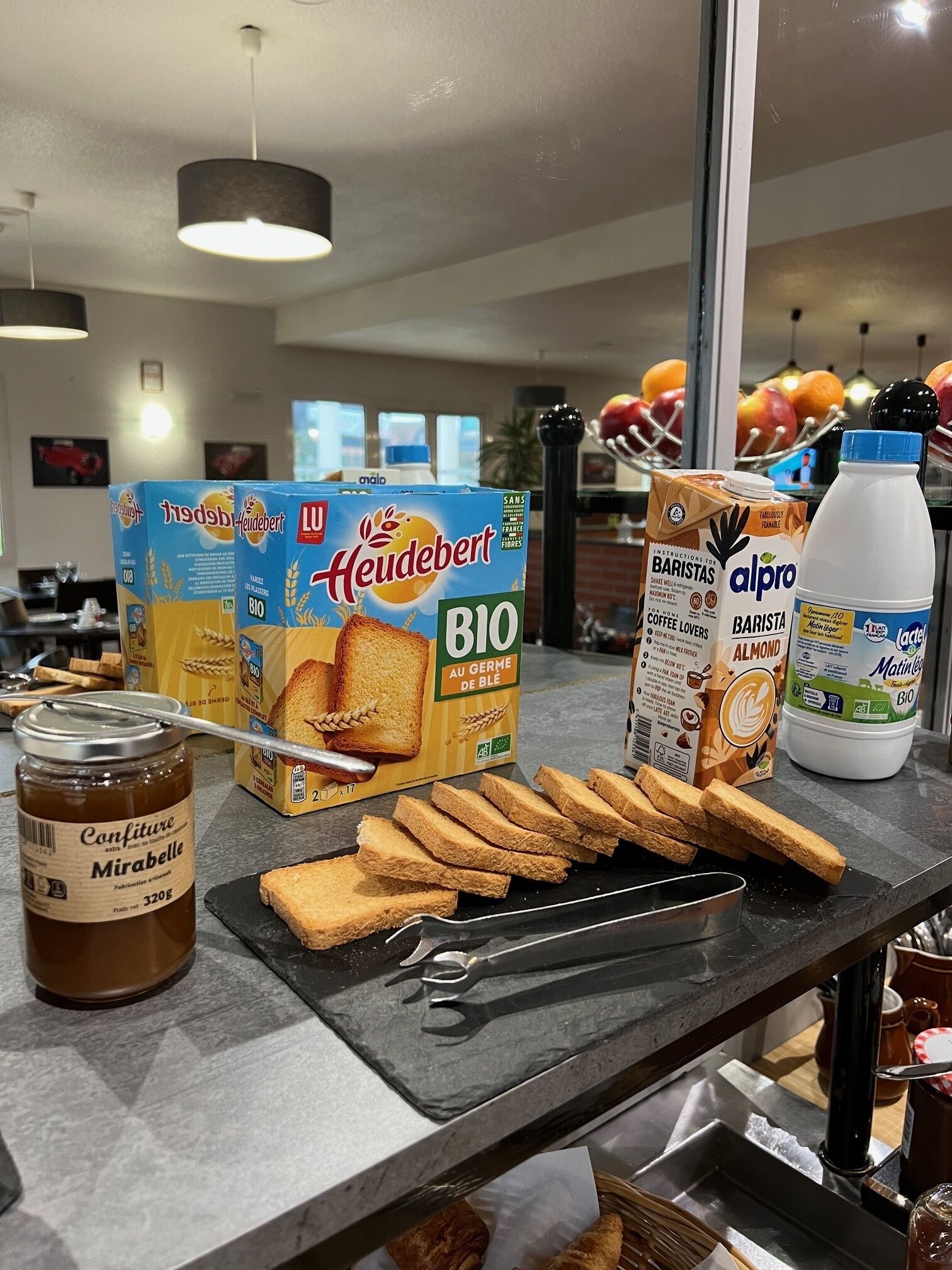 Un plan de travail de cuisine avec du pain, un pot de confiture et des boîtes de pain de mie Heudebert.