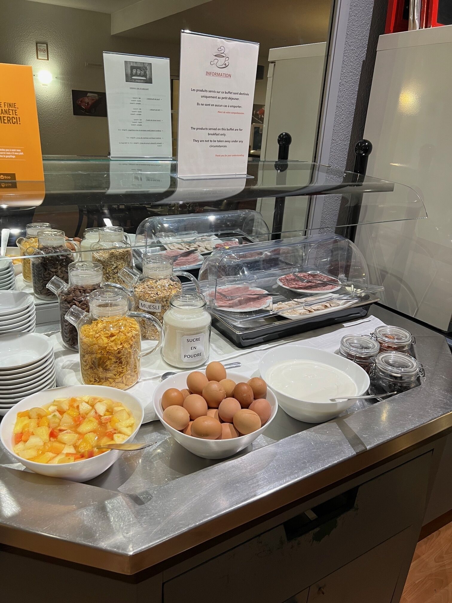 A buffet counter with various food items including fruits, eggs, and condiments.