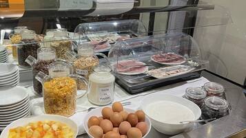 A buffet counter with various food items including fruits, eggs, and condiments.