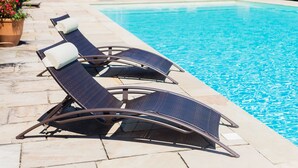A poolside area with lounge chairs and potted plants. - Logis hôtel Les Vignes Blanches (Beaucaire)