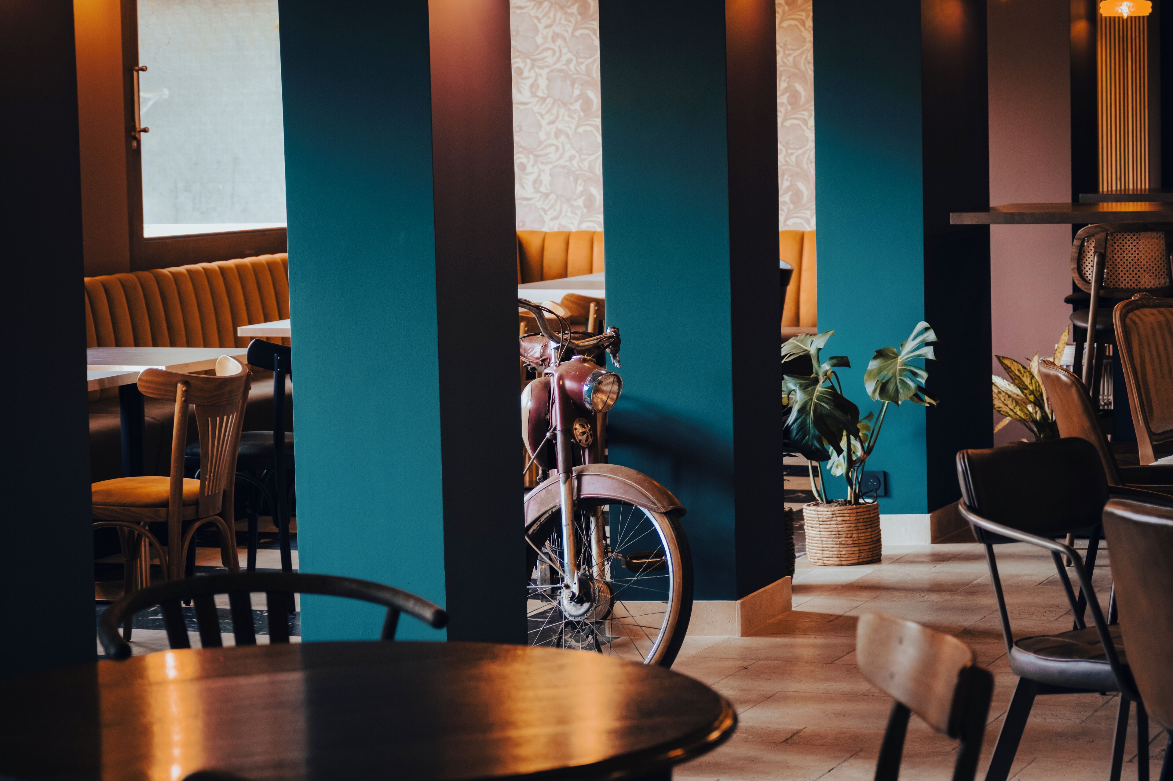 Interior de restaurante con mesas y sillas de madera, y una bicicleta antigua.