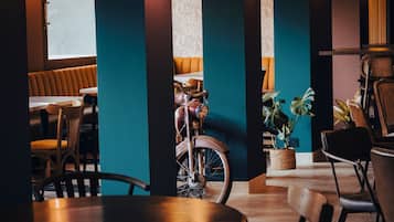 Interior de restaurante con mesas y sillas de madera, y una bicicleta antigua.
