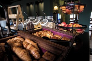 Un bufé de desayuno con bollería, frutas y frascos de conservas.