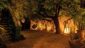 A garden area with a wooden staircase, a wicker chair, and a large potted plant. - Logis hôtel Les Vignes Blanches (Beaucaire)