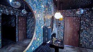 A modern interior with floral wallpaper, a black sink, and disco ball lighting. - Logis hôtel Les Vignes Blanches (Beaucaire)