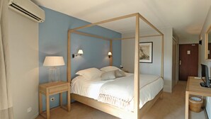 Una cama con dosel de madera, una mesita de noche con lámpara y una lámpara de pared.