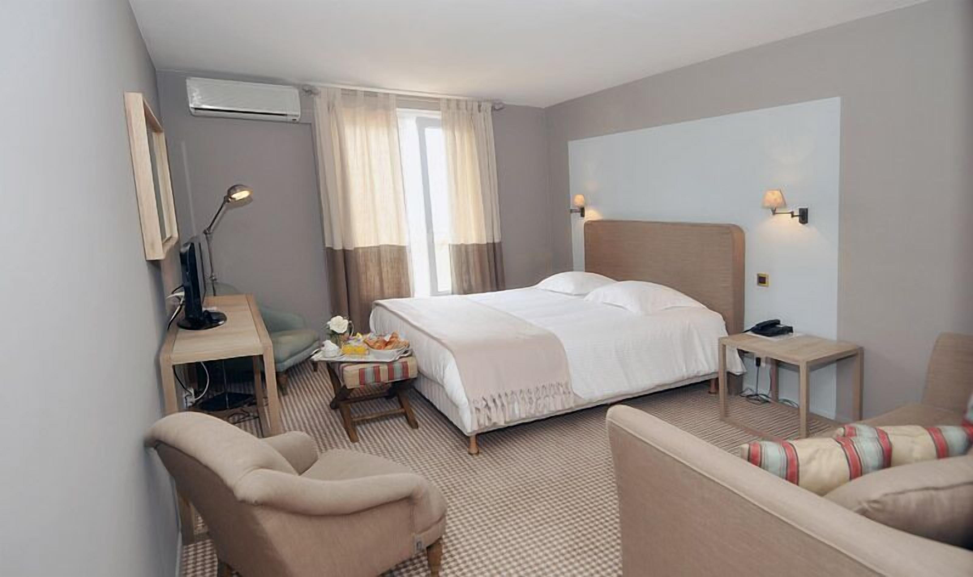 Et hotelværelse med seng, skrivebord, stol, sofa og lampe.