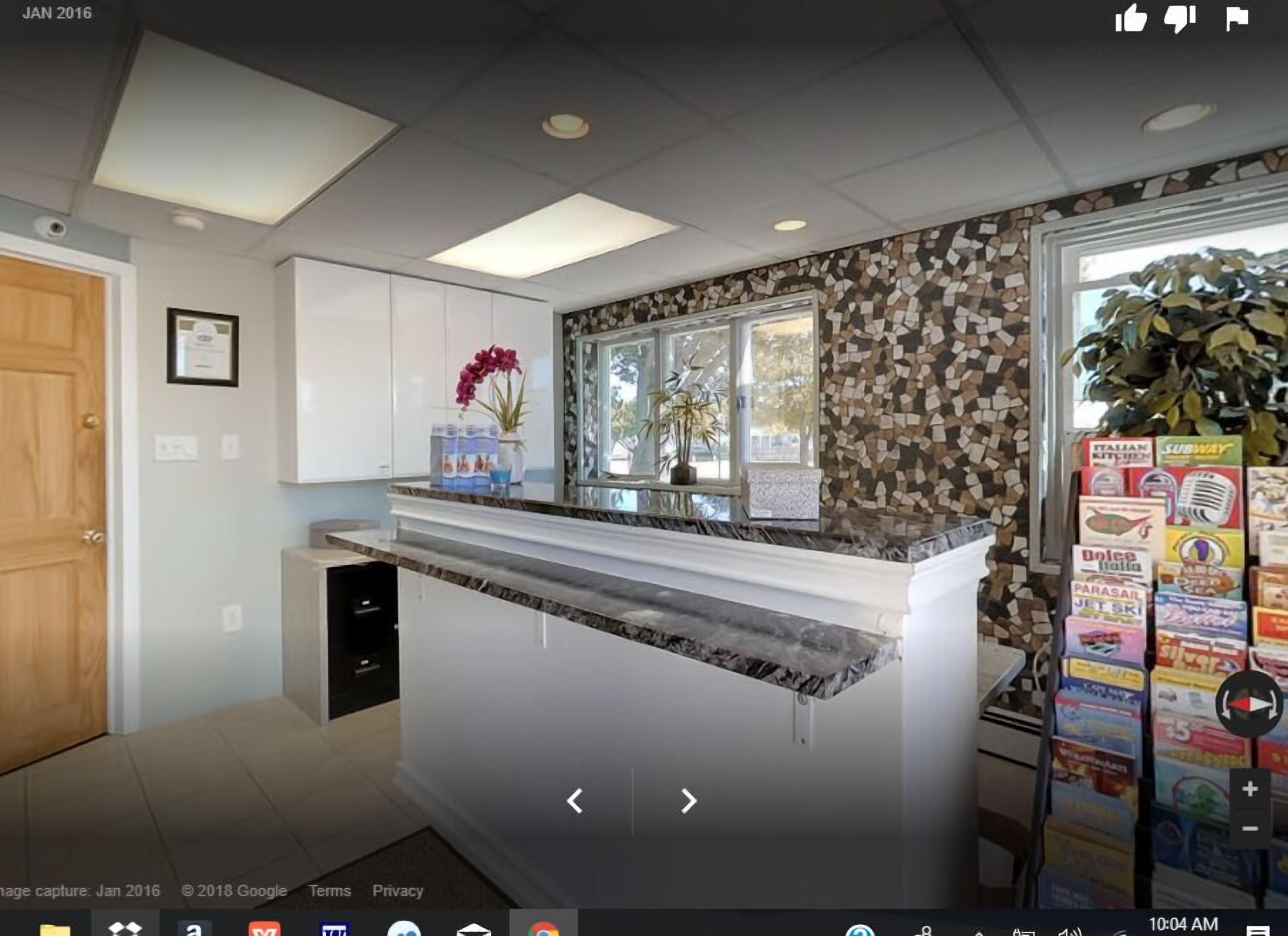 A kitchen with white cabinets, a marble countertop, and a backsplash with a mosaic pattern.